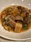 Shallow bowl of beef stew with large chunks of potato, garnished with chopped parsley.