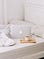 A laptop and a cup of coffee on a white bed.