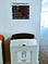Tactile wayfinding board on wall over large waste bin