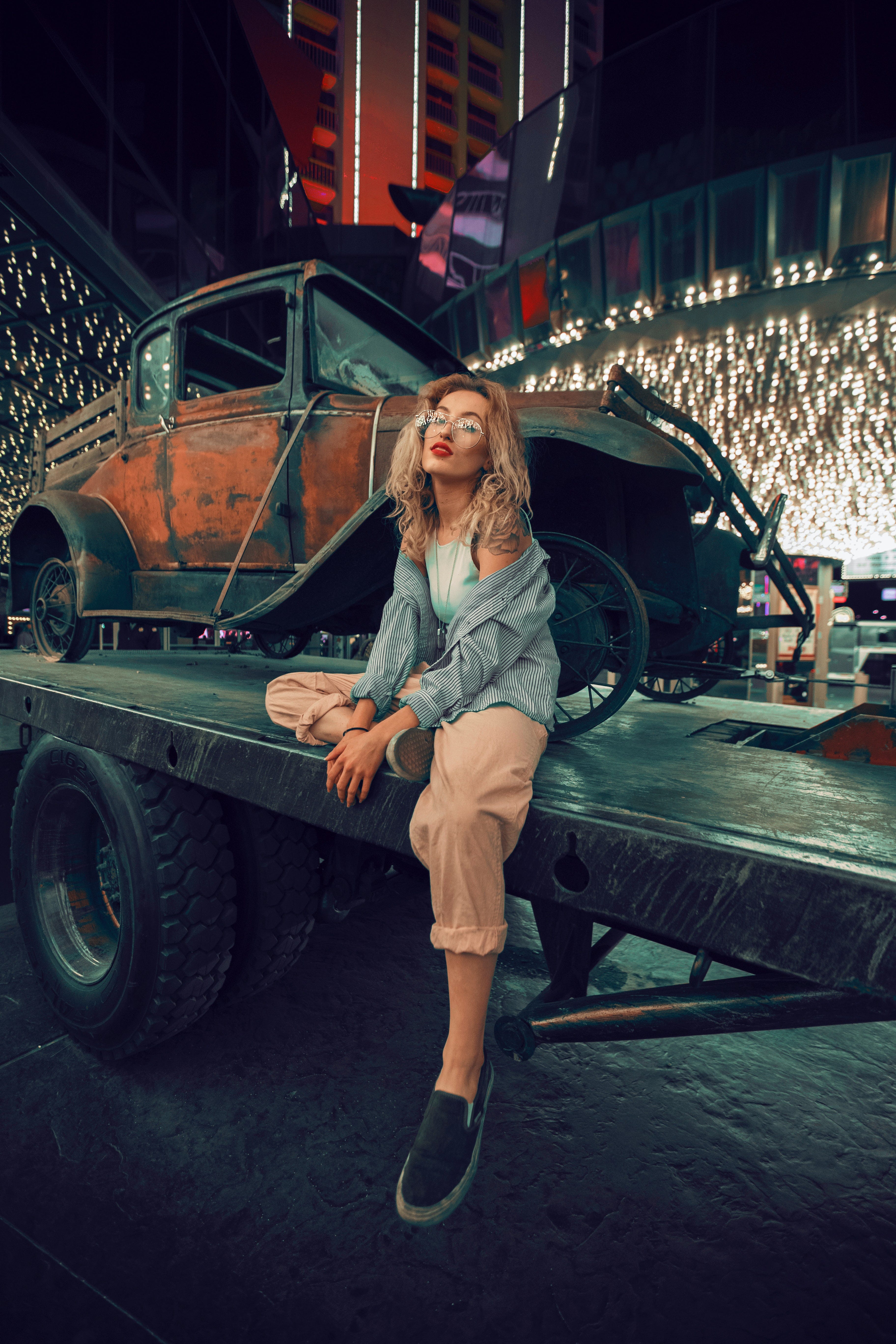 Woman sitting in front of rusty car