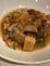 Shallow bowl of beef stew with large chunks of potato, garnished with chopped parsley.