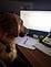 Perra sentada en escritorio mirando la computadora.