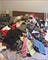 A mountain of clothes, mostly blacks, greys, and pinks, piled atop the author’s bed.