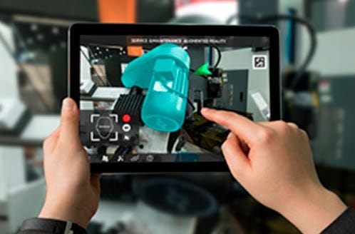 Dispositivo móvel mostra em sua tela instruções com o auxílio da realidade aumentada na indústria e recebe o toque de uma mão que interage com a tela.