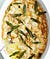 An oval casserole dish of gnocchi gratin garnished with crispy sage leaves.