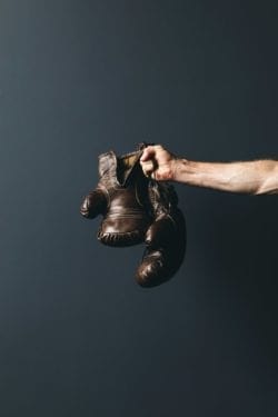a hand holding up leather boxing gloves