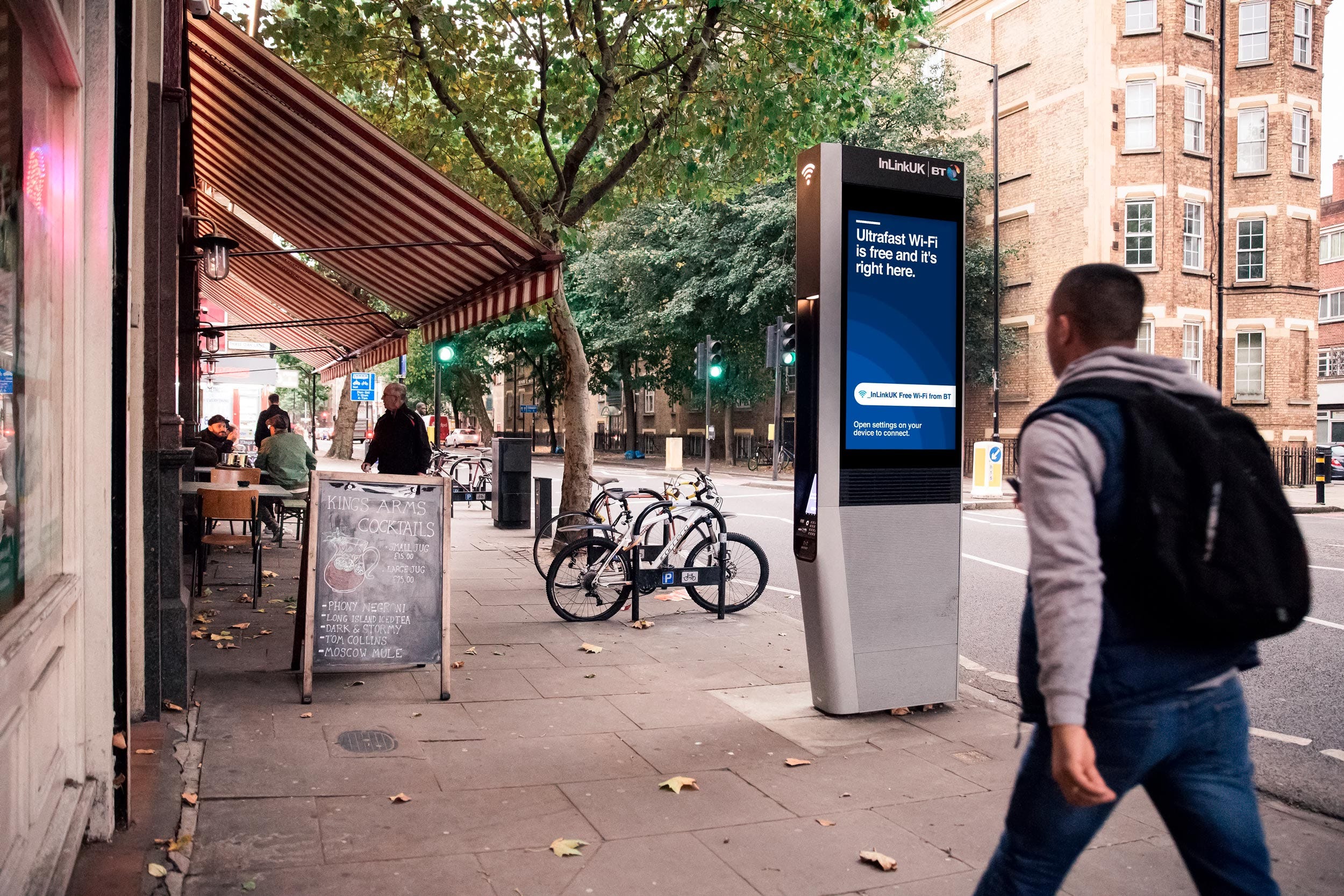 Street photograph of a man walking along the pavement in a city, just before the new kiosk A1 InLink advertising units