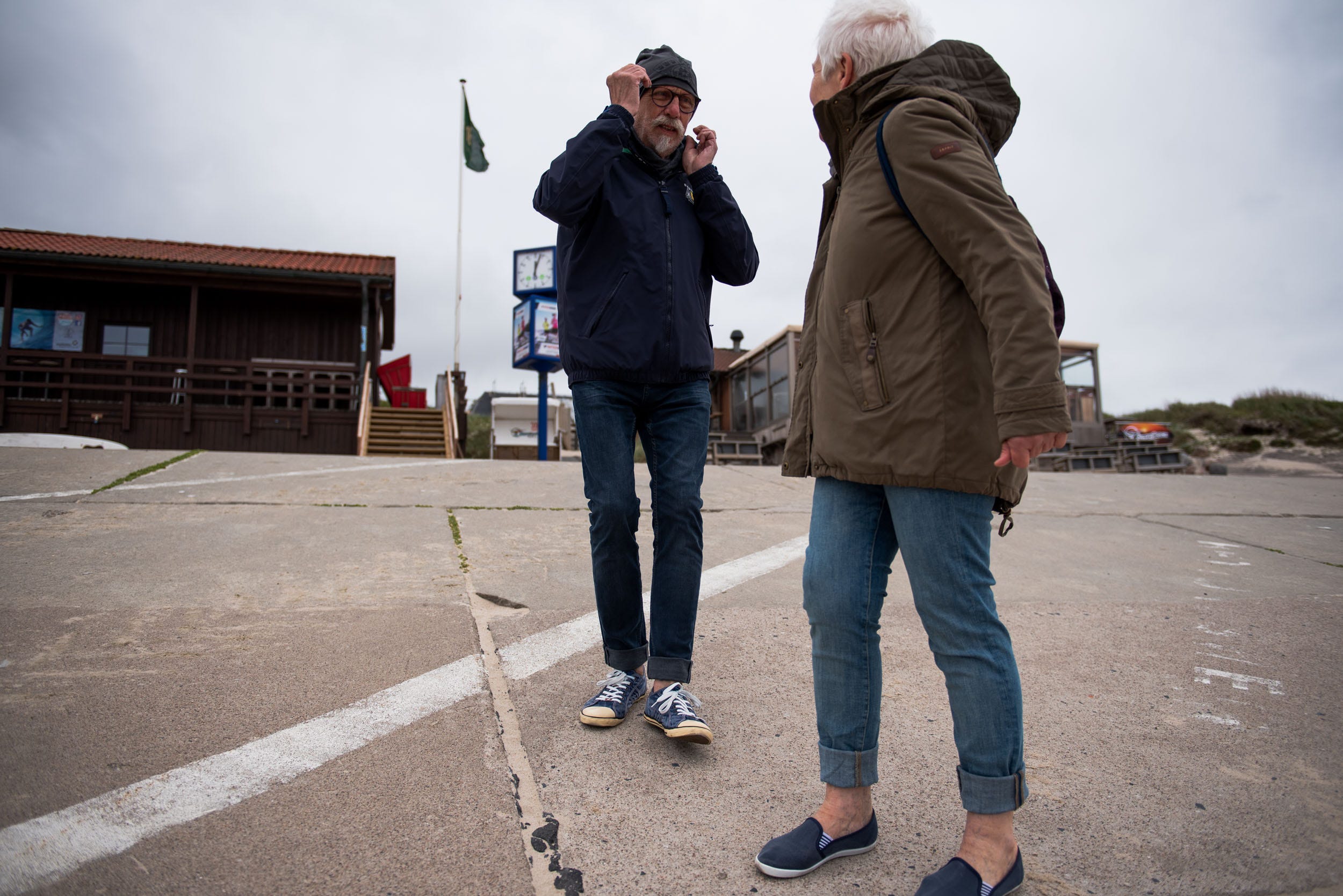 Leaving the promenade, dad secures his hat against the forces of the strong winds. Westerland, Germany, May 22, 2019.