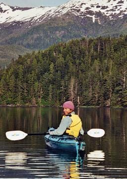 A photo of Marybeth kayaking in Alaska with a forest in the background