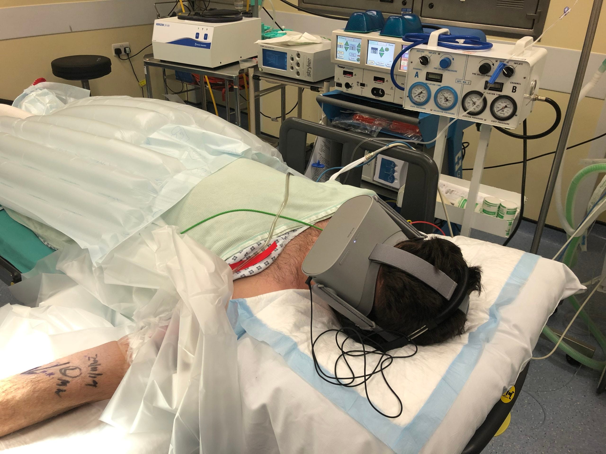 A patient lying in an operating room with a VR headset on. 