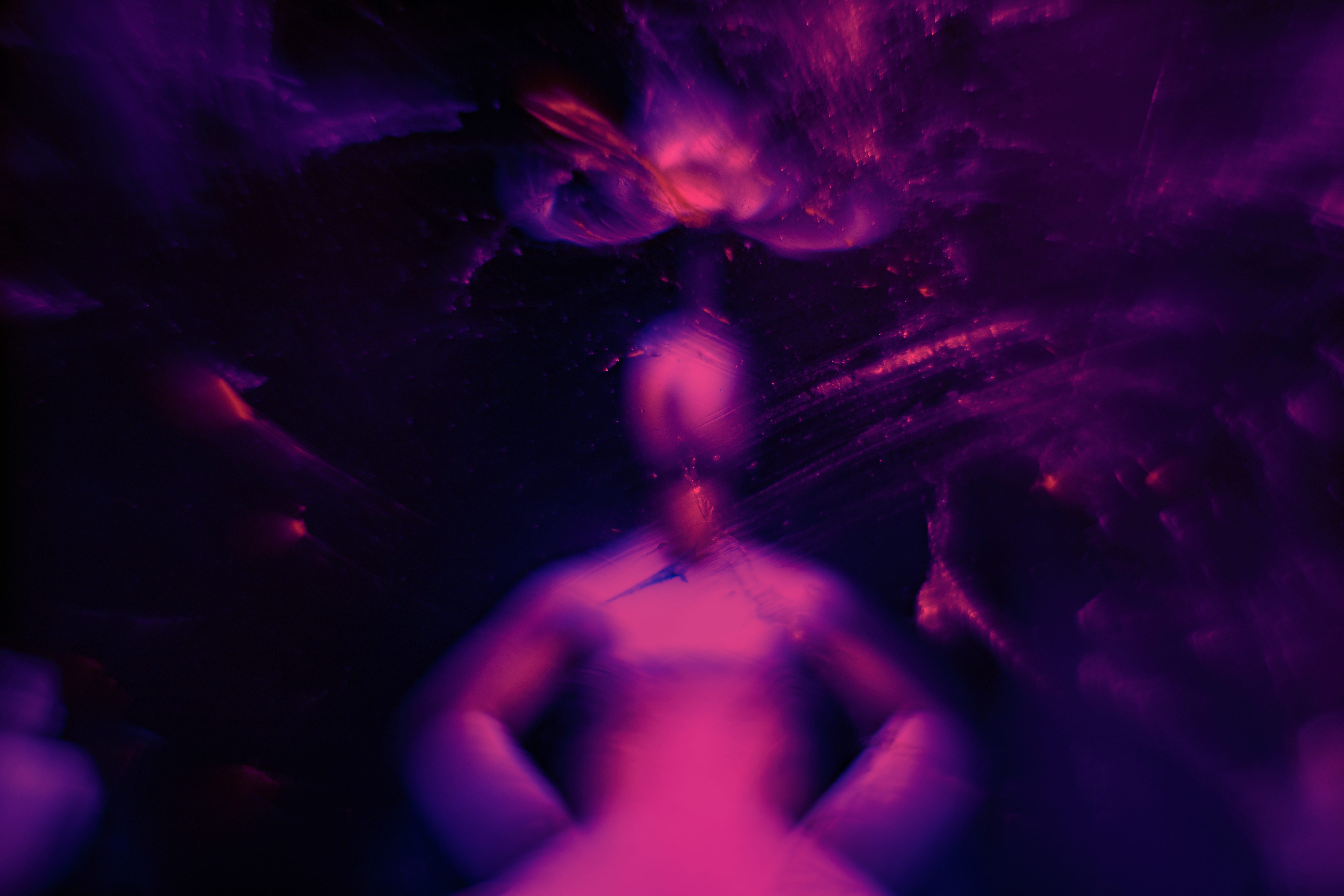 Psychadelic pink and purple picture looks blurrily human with light floating above the head