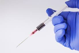 A gloved hand holding a syringe.