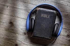 A bible with a blue headset sits on a wooden background