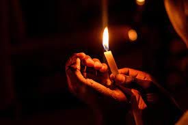 Hands holding a lit candle