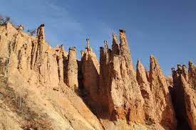 A photo of a rock formation set against blue sky. The rocks are sticking up like spires