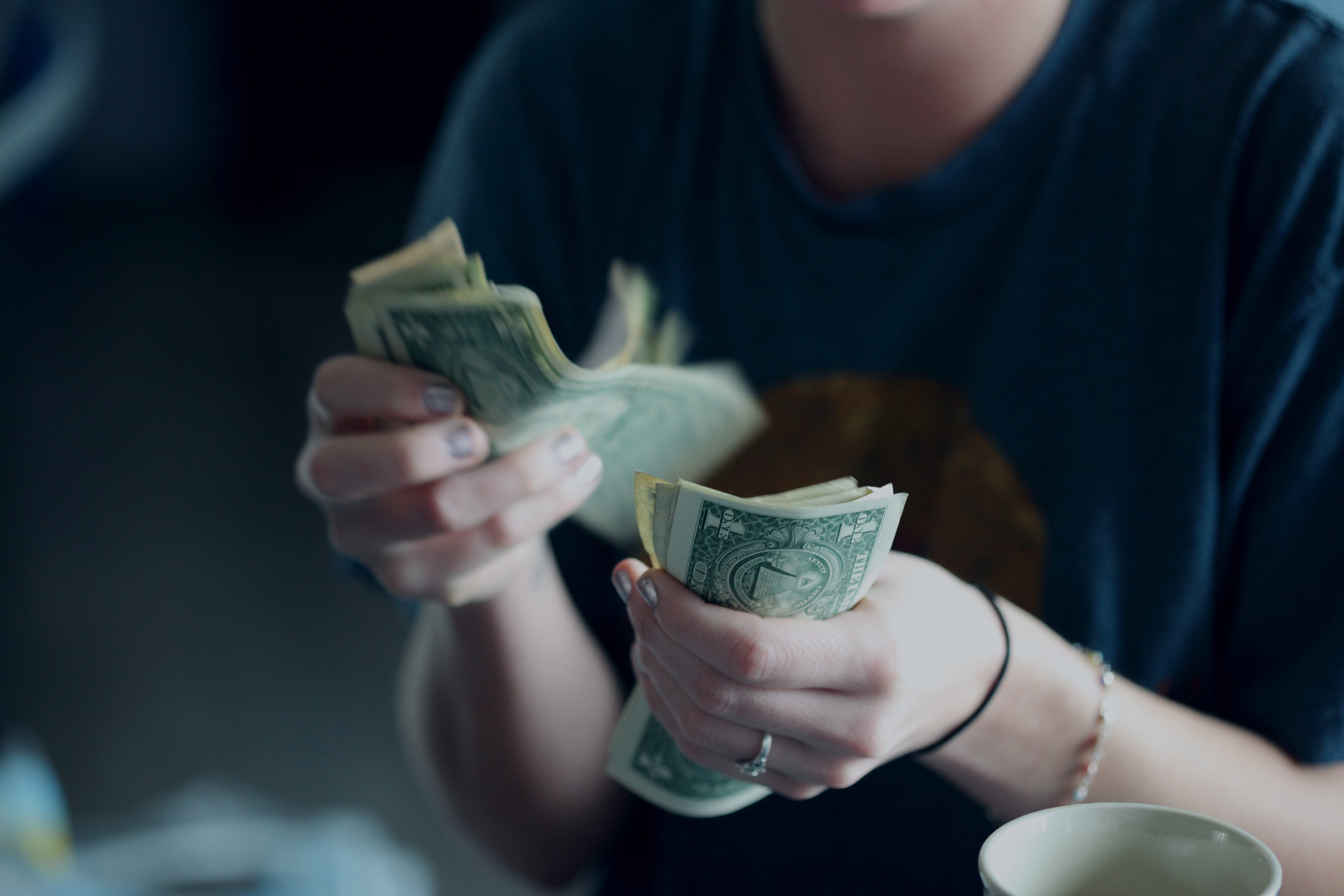 A photo of a person’s hands counting dollar bills — Photo by Sharon McCutcheon on Unsplash