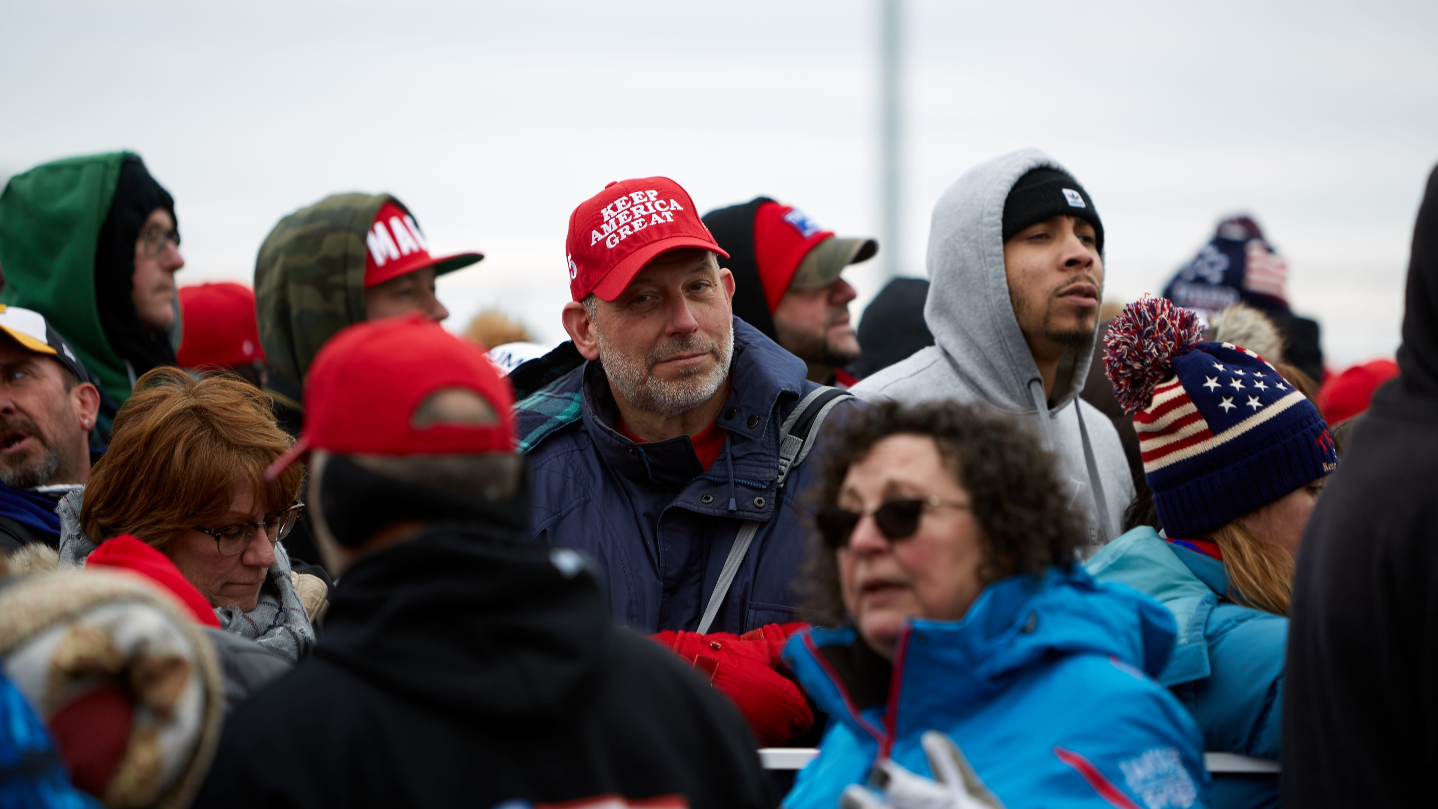 Trump supporters, one man wearing a MAGA hat.