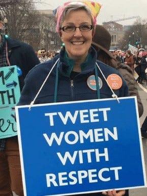 Woman holding a blue sign with “TWEET WOMEN WITH RESPECT” in white lettering