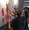 Three people arrange colorful post-it notes on a whiteboard