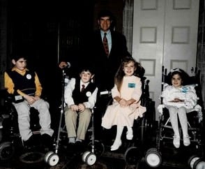 Four children in wheelchairs with older man.