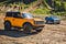 Yellow 2021 Ford Bronco next to a Blue 1966 Ford Bronco in a field