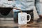Pouring coffee into a white mug that says UGH