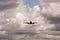 An aeroplane flying under white clouds during daytime