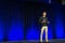 Person on stage talking to an audience.