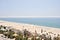 Landscape view of a beach with palm trees, buildings and the ocean.