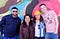 A smiling group of four queer design club members in front of a colorful mural in the Mission.