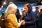 Kamala Harris in a blue suit holds the hands of a senior Iowa caucus-goer in a yellow sweater