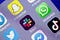 A close up of a phone display with various messaging and social media app icons, featuring the Slack app icon in the center.
