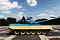 Blue and cream painted tank on a paved plaza with a person sat on it. Blue sky in the background.
