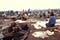 A crowd of people sitting in a muddy field full of garbage.