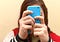Close up of a teenager using her smartphone. Her face is obscured by her phone.