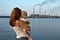 A mother and child look across the water at smokestacks.