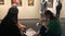 Museum staff members interviewing a visitor in a gallery filled with early modern art works.