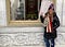 Image from the Twitter account of @DotJenna showing her flashing a peace sign outside a broken Capitol building window.