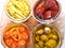 four jars of oil and confit’d veg — parsnip, beet, tomato, and potatoes — in rich color