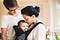 Woman looking at mother kissing baby girl while standing at home
