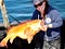 woman holds a large yelloweye rockfish on a boat