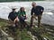three people smile from a river bank