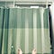 A green hospital curtain hanging in front of an open door. A right and left foot, pale, are visible at the bottom.