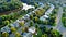 A subdivision with cookie-cutter houses, next to a wooded river.