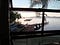 Looking through a window at a ramshackle dock and the sea with small outrigger fishing boats and big bamboo fishing structures scattered around