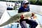 man holds a large gar on a boat