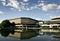 A photograph of The National Archives building under blue skies, reflected in pond, taken at Kew in London, UK.