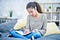 A woman sits cross legged on her bed and writes in her journal.