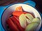 A blue baby’s bowl with sticks of carrot and slices of apple in it