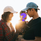 An asian man and woman stand close to each other, the man holding a child in his arms and the two gazing lovingly at it. There’s a large purple question mark covering the child’s face.